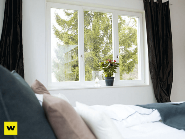 Modernes Schlafzimmer mit großem Fenster, Pflanzen und Blick ins Grüne für Wohnkomfort.